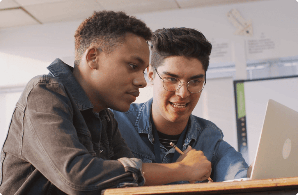 Two students collaborating on a laptop.